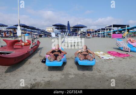 Versilia, Italien. August 2021. Am 22. August 2021 sonnen sich die Menschen an einem Strand in der Versilia, Toskana, Italien. Die Toskana hat mehr als 400 km (250 Meilen) Küste. Der nördliche Teil der Insel, die Versilia genannt wird, hat einen breiten und langen Sandstrand, der kilometerweit von Marina di Carrara bis Torre del Lago Puccini reicht und glamouröse Resorts wie Forte dei Marmi, Marina di Pietrasanta und Viareggio umfasst. Hunderte von Badeanstalten bedecken die Küste, mit Apuanischen Alpen, einer sehr beeindruckenden Bergkette im Hintergrund.(Foto: Elisa Gestri/Sipa USA) Quelle: SIPA USA/Alamy Live News Stockfoto