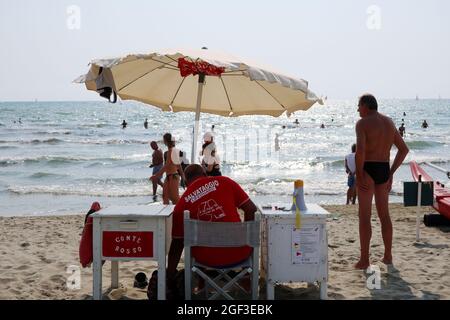 Versilia, Italien. August 2021. Rettungsschwimmer am Meer in der Versilia, Toskana, Italien, am 22. August 2021. Die Toskana hat mehr als 400 km (250 Meilen) Küste. Der nördliche Teil der Insel, die Versilia genannt wird, hat einen breiten und langen Sandstrand, der kilometerweit von Marina di Carrara bis Torre del Lago Puccini reicht und glamouröse Resorts wie Forte dei Marmi, Marina di Pietrasanta und Viareggio umfasst. Hunderte von Badeanstalten bedecken die Küste, mit Apuanischen Alpen, einer sehr beeindruckenden Bergkette im Hintergrund.(Foto: Elisa Gestri/Sipa USA) Quelle: SIPA USA/Alamy Live News Stockfoto