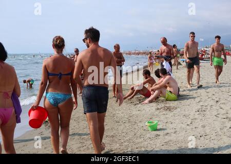 Versilia, Italien. August 2021. Am 22. August 2021 wandern die Menschen in der Versilia, Toskana, Italien, am Ufer. Die Toskana hat mehr als 400 km (250 Meilen) Küste. Der nördliche Teil der Insel, die Versilia genannt wird, hat einen breiten und langen Sandstrand, der kilometerweit von Marina di Carrara bis Torre del Lago Puccini reicht und glamouröse Resorts wie Forte dei Marmi, Marina di Pietrasanta und Viareggio umfasst. Hunderte von Badeanstalten bedecken die Küste, mit Apuanischen Alpen, einer sehr beeindruckenden Bergkette im Hintergrund.(Foto: Elisa Gestri/Sipa USA) Quelle: SIPA USA/Alamy Live News Stockfoto