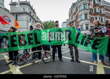 London, Großbritannien. 23. August 2021. Klimaaktivisten von Extinction Rebellion vor der U-Bahnstation Leicester Square halten während eines Protestes in Covent Garden ein Banner hoch. Die Gruppe hat angekündigt, dass sie in den nächsten zwei Wochen Proteste in der Hauptstadt ausrichten wird, um das Bewusstsein für die Auswirkungen des Großkapitals auf den Klimawandel zu schärfen. Kredit: Stephen Chung / Alamy Live Nachrichten Stockfoto