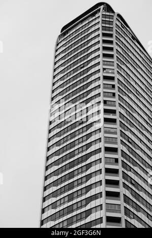 Vertikale Graustufenaufnahme eines hohen modernen Gebäudes mit vielen Fenstern Stockfoto