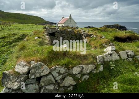 Das Haus oder das Häuschen auf Eilean an Taighe auf den Shiant Isles mit den Ruinen einer älteren Wohnung im Vordergrund. Stockfoto