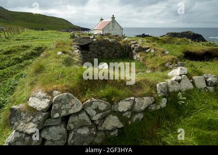 Das Haus oder das Häuschen auf Eilean an Taighe auf den Shiant Isles mit den Ruinen einer älteren Wohnung im Vordergrund. Stockfoto