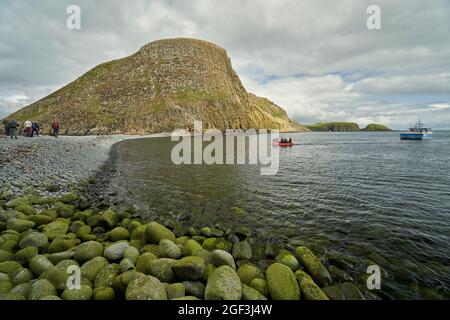 Besucher auf einem Tagesausflug zu den Shiant Isles, die auf der felsigen Landenge ankommen, die Garbh Eilean und Eileen an Taighe verbindet. Stockfoto