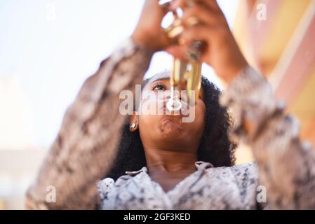 Low-Angle-Ansicht einer afrikanischen Frau, die draußen in der Stadt Trompete spielt Stockfoto