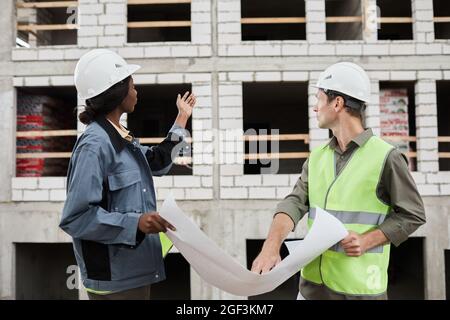 Seitenansicht Porträt von zwei Ingenieurinnen in Harthüten auf der Baustelle Stockfoto
