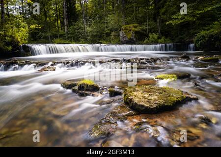 Eine idyllische Flusslandschaft im Wald mit einem kleinen Wasserfall Stockfoto