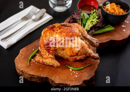 Gebratenes ganzes Huhn auf Holzkohle mit Bulgur-Pilaf auf Holzbrett gekocht. Stockfoto