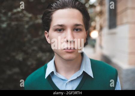 Hübscher Teenager Junge Student 16 - 17 Jahre alt tragen Schuluniform posiert im Freien aus der Nähe. Zurück zur Schule. Blick auf die Kamera. Teenagerhood. 20s. Stylisch Stockfoto