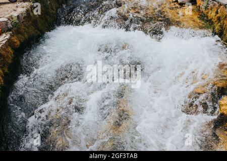 Hoch anwinklige Aufnahme eines schäumenden Wasserstroms über schroffen Steinen und Felsen Stockfoto