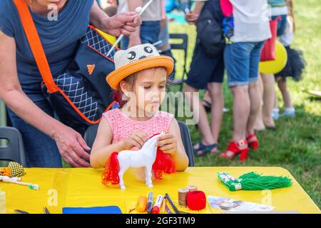 Zaporizhia, Ukraine- 19. Juni 2021: Charity Familienfest: Mädchen spielt mit Spielzeug Pferd im Freien Kunst und Handwerk Workshop Stockfoto