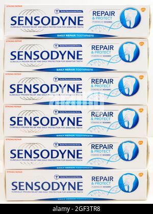 Nahaufnahme von sechs ungeöffneten, vertikal gestapelten Boxen aus Sensodyne Repair & Protect Zahnpasta-Röhrchen, formuliert für empfindliche Zähne. Stockfoto