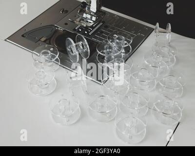 Klare Kunststoff-Spulen für Nähmaschine. Viele leere Spulen für Gewinde. Nähzubehör Stockfoto