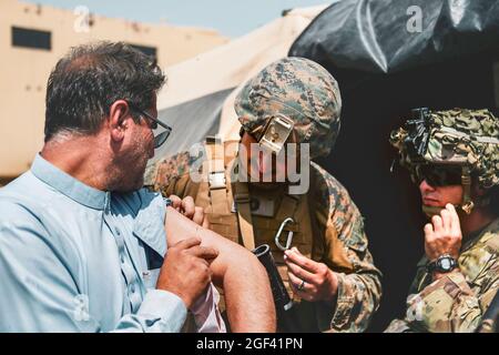 Ein Mitarbeiter der 24. Marine Expeditionary Unit (MEU) und ein Medic der 82. Airborne Division helfen einem Evakuierten während einer Evakuierung am Hamid Karzai International Airport, Kabul, Afghanistan, am 22. August. US-Dienstmitglieder unterstützen das Außenministerium bei einer nicht-kämpferischen Evakuierungsoperation (NEO) in Afghanistan. (USA Marine Corps Foto von Sgt. Isaiah Campbell über American Photoarchive/Alamy) Stockfoto