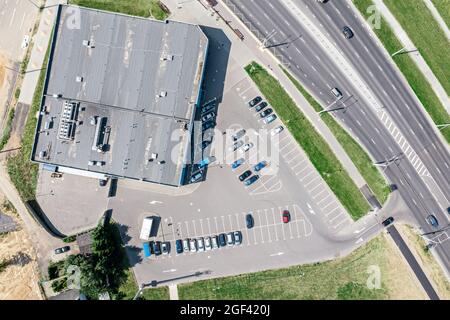 Parkplatz mit Reihen von geparkten Autos in der Nähe von Einkaufszentrum in sonnigen Sommertag. Drohne Foto. Stockfoto