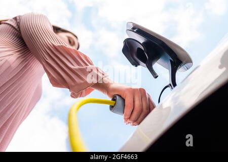 Weibliche Hände, die ein Ladegerät in die Steckdose stecken Stockfoto