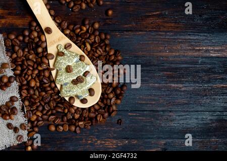 Ein Holzlöffel mit Kaffeespielzeug weihnachtsbaum und Kaffeebohnen auf einem hölzernen Hintergrund Stockfoto