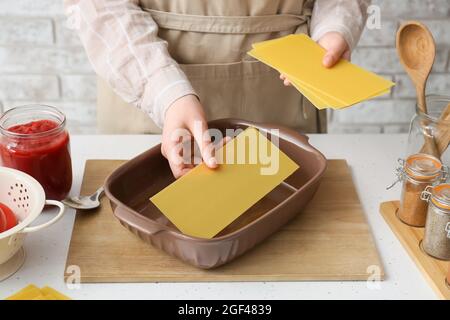 Frau bereitet leckere Lasagne am Tisch in der Küche, Nahaufnahme Stockfoto