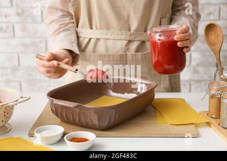 Frau bereitet leckere Tomatenlasagne am Tisch in der Küche zu, Nahaufnahme Stockfoto
