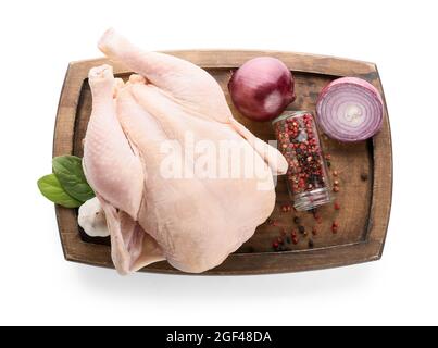 Brett mit ganz rohem Huhn und Gewürzen auf weißem Hintergrund Stockfoto