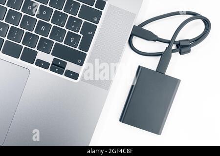 Externe Festplatte, die an einen modernen Laptop angeschlossen ist. Draufsicht Stockfoto