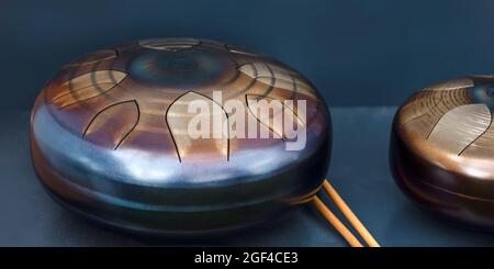 Stahlzunge, Trommel. Klangschale, Stahltrommel und Drumsticks. Instrument für Klangwellentherapie und Meditation, Heilung. Stockfoto