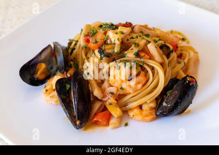 Linguine mit Meeresfrüchten. Typisches Gericht der italienischen Küche, bestehend aus Pasta (Linguine), gekrönt mit Tomatensauce, Garnelen, Tintenfisch und Meeresfrüchten. Stockfoto