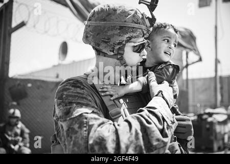 US Marine mit der 24. Marine Expeditionary Unit (MEU) beruhigt ein weinendes Kleinkind während einer Evakuierung am Hamid Karzai International Airport, Afghanistan, August 22. US-Dienstmitglieder unterstützen das Außenministerium bei einer nicht-kämpferischen Evakuierungsoperation (NEO) in Afghanistan. (USA Marine Corps Foto von Staff Sgt. Victor Mancilla über American Photoarchive/Alamy) Stockfoto