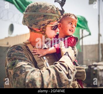 US Marine mit der 24. Marine Expeditionary Unit (MEU) beruhigt ein weinendes Kleinkind während einer Evakuierung am Hamid Karzai International Airport, Afghanistan, August 22. US-Dienstmitglieder unterstützen das Außenministerium bei einer nicht-kämpferischen Evakuierungsoperation (NEO) in Afghanistan. (USA Marine Corps Foto von Staff Sgt. Victor Mancilla über American Photoarchive/Alamy) Stockfoto