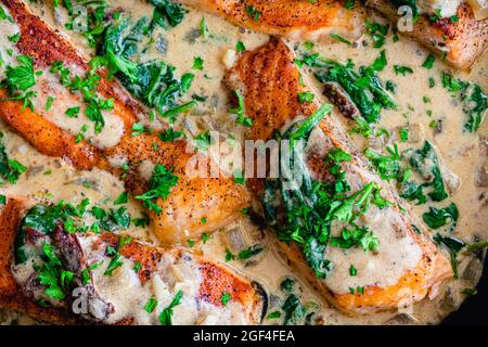Cremige Knoblauchbutter toskanischer Lachs in einer Pfanne: Lachsfilets in einer cremigen Parmesan-Sauce mit Spinat und sonnengetrockneten Tomaten Stockfoto