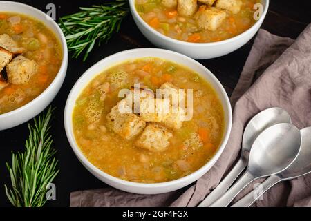 Cremige weiße Bohnensuppe mit Rosmarin und Pancetta: Schüsseln Cannellini-Bohnensuppe mit Gemüse, Rosmarin und Pancetta Stockfoto