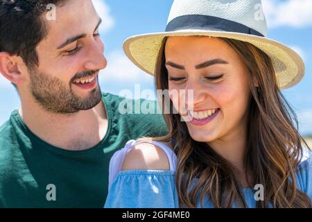 Mann, der an sonnigen Tagen lächelnde Freundin mit Hut ansieht Stockfoto