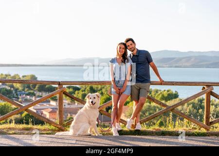 Pärchen lehnt sich mit Hund an Geländer Stockfoto