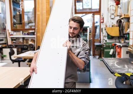 Männlicher Handwerker mit weißem Brett in der Werkstatt Stockfoto