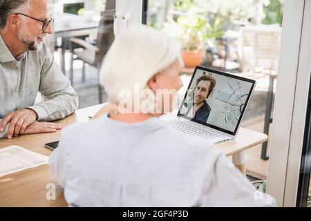 Im Heimbüro führen männliche und weibliche Geschäftsleute Videoanruf mit Kollegen auf einem Laptop durch Stockfoto