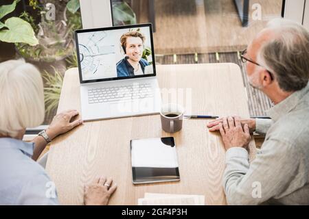 Reife Geschäftsleute, die im Heimbüro Videoanruf mit einem männlichen Kollegen auf einem Laptop tätigen Stockfoto