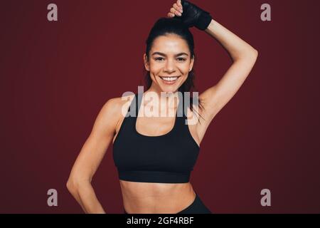 Glückliche weibliche Athletin vor kastanienbraunem Hintergrund Stockfoto