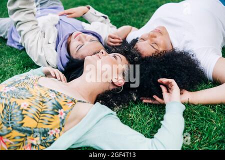 Junge Freundinnen und Freundinnen liegen auf Gras im Park Stockfoto