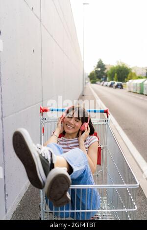 Lächelnde Frau mit geschlossenen Augen und Musik im Warenkorb Stockfoto