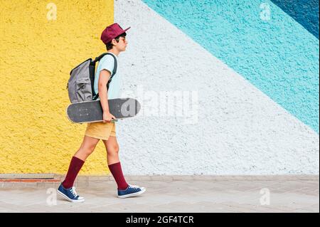 Junge mit Mütze und Skateboard auf Fußpfad stehen Stockfoto