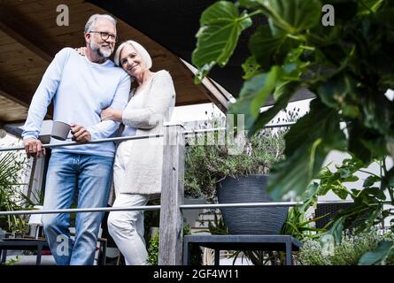 Lächelnde Frau, die sich an einen Mann lehnt, während sie am Geländer steht Stockfoto