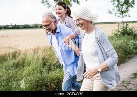 Glückliche Familie beim Spielen, während sie auf der Wiese zusammen läuft Stockfoto