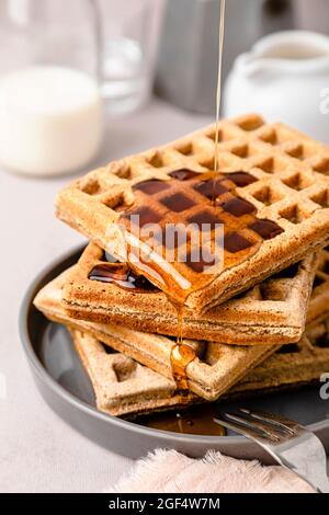 Ahornsirup, der auf einen Stapel frischer Waffeln gießt Stockfoto