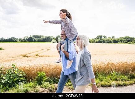 Großeltern wandern mit verspielter Enkelin an sonnigen Tagen Stockfoto