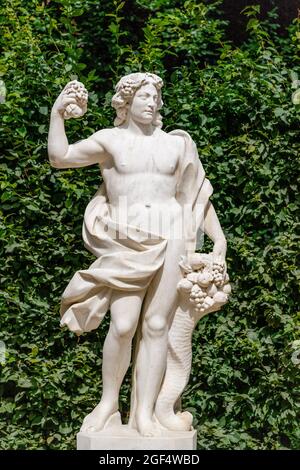 Statue mit Füllhorn auf grünem Blatthintergrund am Palast von Sanssouci. Potsdam, Deutschland Stockfoto