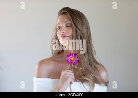 Junge schöne Frau mit Gänseblümchen vor weißem Hintergrund Stockfoto