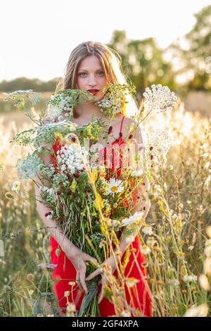 Blonde junge Frau mit Wildblumen auf dem Feld Stockfoto