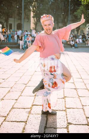 Fröhlicher schwuler Mann mit Regenbogenfahne auf dem Fußweg Stockfoto