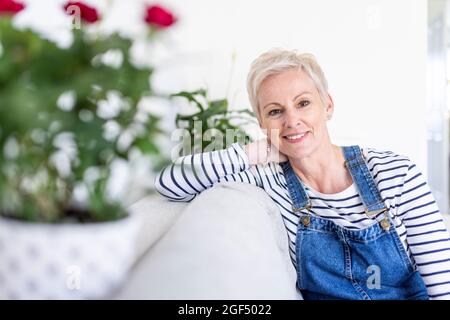 Reife Frau sitzt auf dem Sofa zu Hause Stockfoto