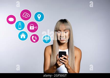 Blonde Frau mit Apps auf dem Smartphone über weißem Hintergrund Stockfoto